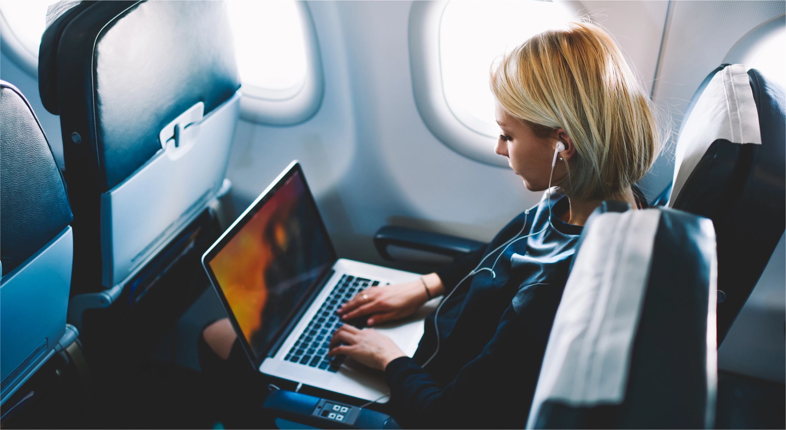 Девушка работает за ноутбуком в самолете