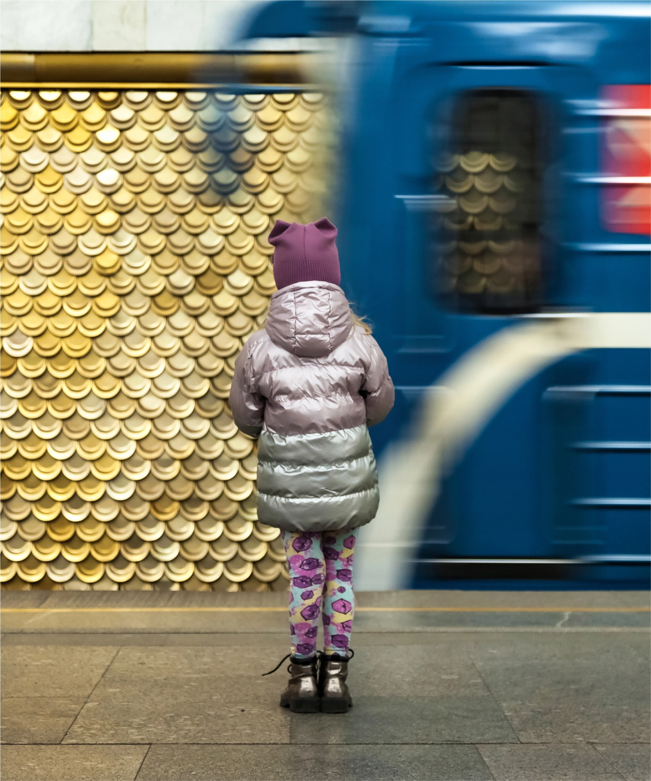 Девочка ждет подъезжающего вагона метро