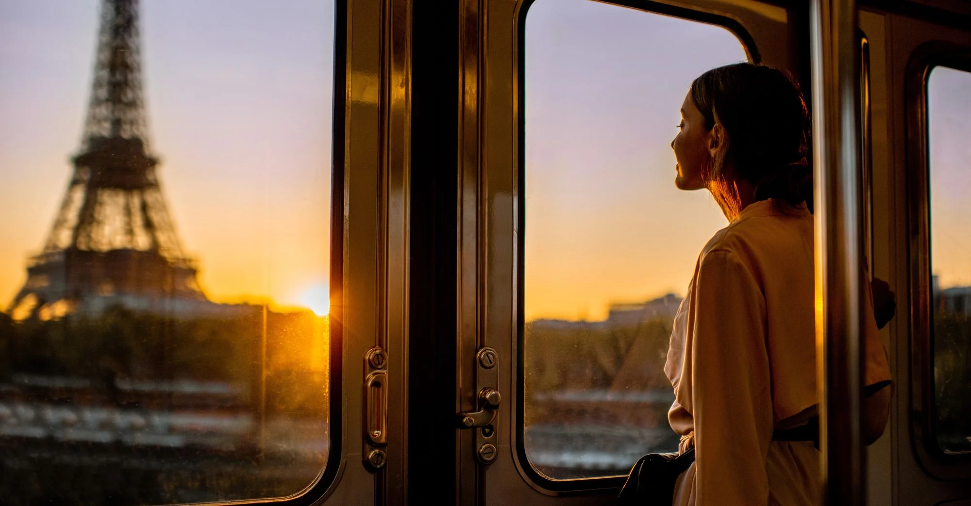 stock-photo-young-woman-enjoying-view-on-the-eiffel-tower-from-the-subway-train-during-the-sunrise-in-paris-1201269166